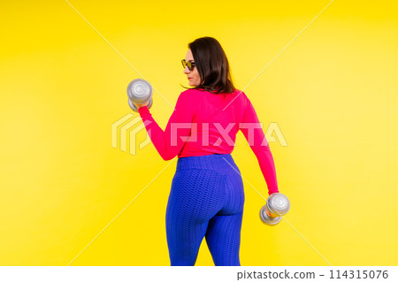 Sporty plump woman doing exercises with dumbbells. Sports motivation and healthy lifestyle 114315076