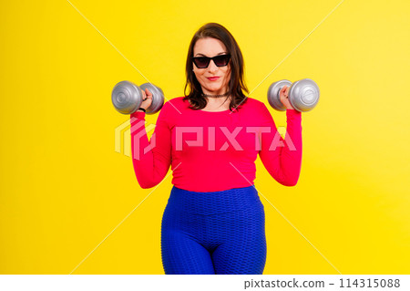 Sporty plump woman doing exercises with dumbbells. Sports motivation and healthy lifestyle 114315088