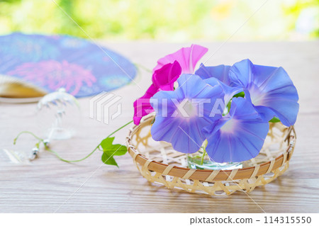 An arrangement of morning glory flowers picked from the garden, a fan and a wind chime 114315550