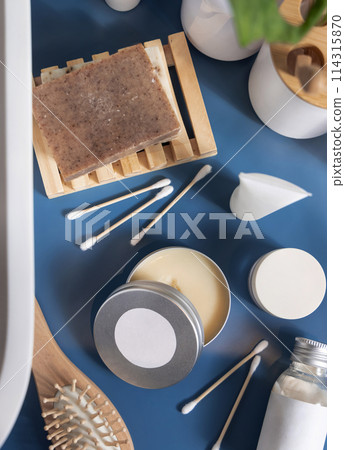 Opened body butter jar near personal care products on blue top view, cosmetic mockup 114315870