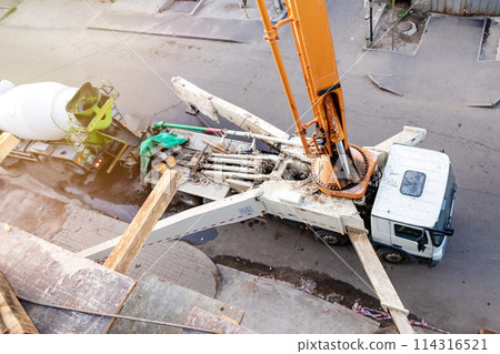 Top-Down Perspective: Concrete Pump Truck Transfers Mixer Truck Load for Floor Pouring at Construction Site. 114316521