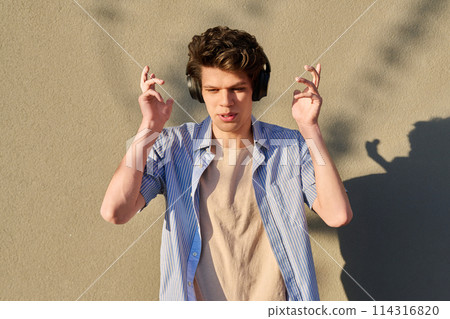 Young handsome male in wireless headphones listening to music Young handsome male in wireless headphones listening to music 114316820