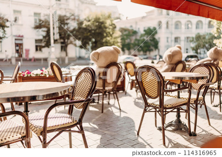 A restaurant with a lot of chairs and tables. There are two teddy bears on the tables. A restaurant with a lot of chairs and tables. There are two teddy bears on the tables. 114316965
