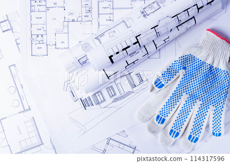 Builder's tools on the scheme of the house. Preparing to build a house. Builder's gloves and blueprints. 114317596