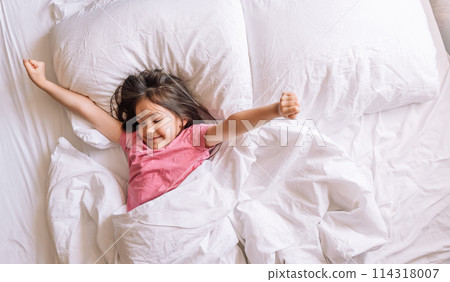 Little girl in pink pajamas woke up in a white bed 114318007