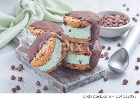 Mint chocolate chips ice cream and chocolate chips cookies sandwiches, on wooden board, horizontal 114318055
