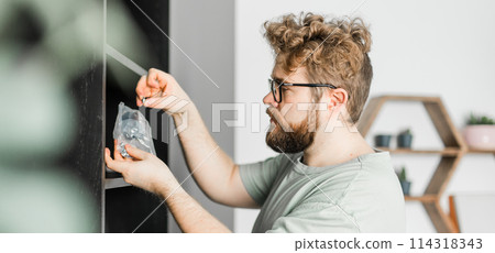 Banner bearded millennial man assemble his bookcase. He uses tools for furniture copy space. Furniture for the interior room or apartments Banner bearded millennial man assemble his bookcase. He uses tools for furniture copy space. Furniture for the interior room or apartments 114318343