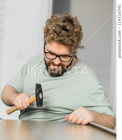 Young attractive man assembles furniture - handwerker and interior objects concept Young attractive man assembles furniture - handwerker and interior objects concept 114318345