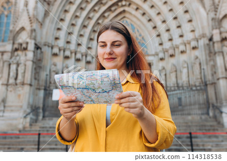 Young woman tourist with paper map standing in front of the famous saint Eulalia church in Barcelona. Concept of travel, tourism and vacation in city. Cathedral of Barcelona 114318538