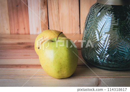 Vase with blue flowers and green apples on a wooden background. Vase with blue flowers and green apples on a wooden background. 114318617