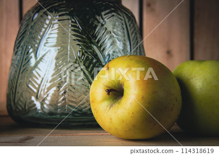 Vase with blue flowers and green apples on a wooden background. Vase with blue flowers and green apples on a wooden background. 114318619