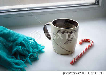 A mug of hot coffee is on the windowsill. 114319195