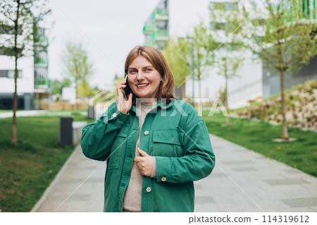 Happy 30s woman talking phone and look happy outdoors Urban lifestyle concept. Summer time. Beautiful woman on the city street. 114319612