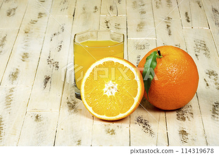 Oranges and glass of orange juice on wooden surface 114319678