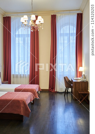 Part of two beds in a tourist resort hotel room with a desk in the corner. A hotel room with a copy space. High quality photo Part of two beds in a tourist resort hotel room with a desk in the corner. A hotel room with a copy space. High quality photo 114320203