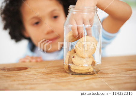 Cute, cookie jar and boy child by the kitchen counter eating a sweet snack or treat at home. Smile, dessert and hungry young kid enjoying biscuits by a wooden table in a modern family house. 114322315