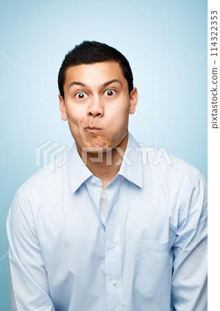 Funny face, goofy and portrait of comic man in studio isolated on blue background for expression. Comedy, humor and joking with playful or silly business person having fun in shirt for fashion Funny face, goofy and portrait of comic man in studio isolated on blue background for expression. Comedy, humor and joking with playful or silly business person having fun in shirt for fashion 114322353