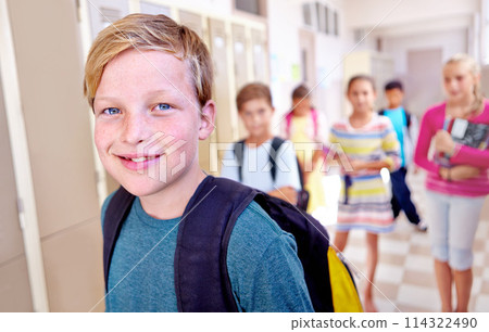 Student, portrait and kid with smile in hallway with education, study and backpack for back to school. Youth, young boy and learning with friends on campus with children and happy in a corridor 114322490