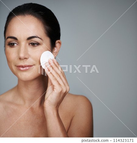 Mature woman, pad and hygiene in studio, skin care and facial treatment on gray background. Female person, cotton and swab for grooming in daily routine, mockup space and dermatology to remove makeup 114323171