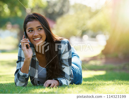 Phone call, relax and woman in a park, sunshine and happiness with conversation and network. Person, outdoor and girl with a smartphone or summer with weekend break and cheerful with a contact or app 114323199