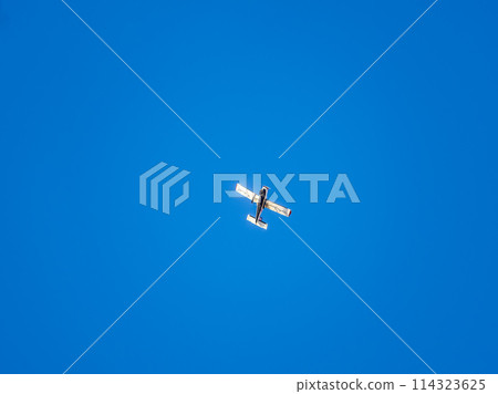 Small ultralight airplane with overhead wing and single propeller flying in sunset sky. Small ultralight airplane with overhead wing and single propeller flying in sunset sky. 114323625