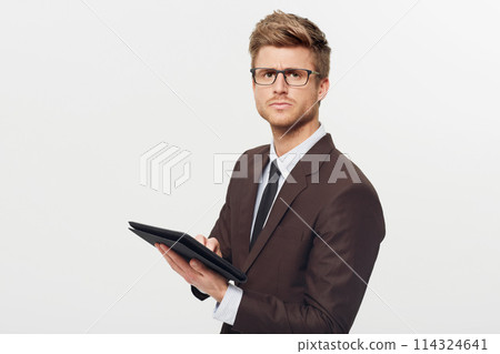 Portrait, tablet and glasses with a business man in studio isolated on a white background for management. Corporate, technology and planning with a serious young employee in eyewear for research 114324641