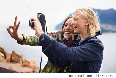 Happy woman, friends and laughing with peace sign or camera for funny photography or moments together in nature. Female person with smile for photo, picture or memories of emoji on outdoor holiday 114324750