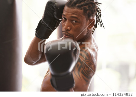 Fitness, portrait and black man with boxing gloves in gym for challenge, fight and competition training. Power, muscle and serious face of champion boxer at workout with confidence in sports club. Fitness, portrait and black man with boxing gloves in gym for challenge, fight and competition training. Power, muscle and serious face of champion boxer at workout with confidence in sports club. 114324932