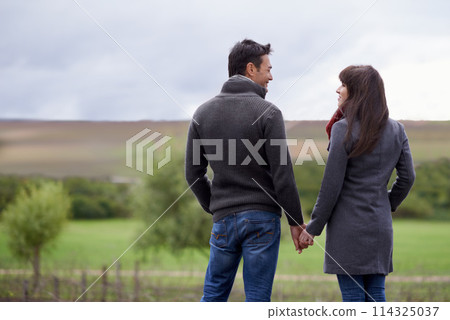 Couple, hold and hands in nature with love on morning walk for scenery, adventure and vacation for honeymoon. Man, woman and relationship with commitment for marriage, smiling and support with care 114325037