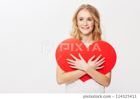 Young woman, red heart or happiness in studio for wellness, love or romantic review on valentines day. American model, positive and smile with care symbol for support and opinion by white background Young woman, red heart or happiness in studio for wellness, love or romantic review on valentines day. American model, positive and smile with care symbol for support and opinion by white background 114325411