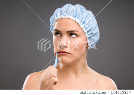 This is the last thing I wanted to do. a young woman brushing her teeth against a studio background. 114325504
