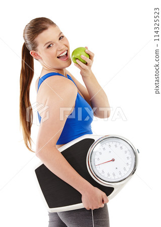 Portrait of woman, apple and scale in studio for measurement, smile and excited for results of diet. Female person, body and care for calories target, weight loss and nutrition in white background 114325523