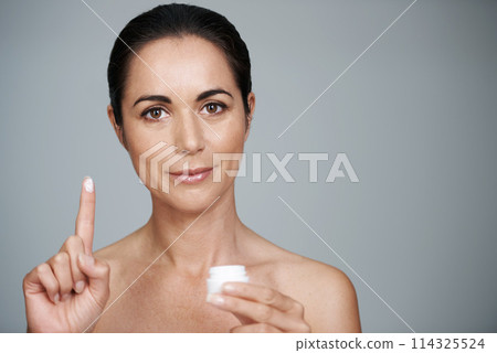 Stay beautiful for longer. Cropped portrait of a beautiful mid adult woman showing the moisturizer she uses. 114325524