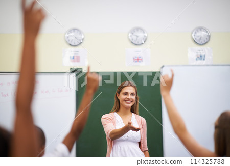 Teacher, hands and children in classroom with question, learning and discussion for education or why. Woman, school kids and happy with studying, knowledge and raised hand for scholarship or lesson 114325788