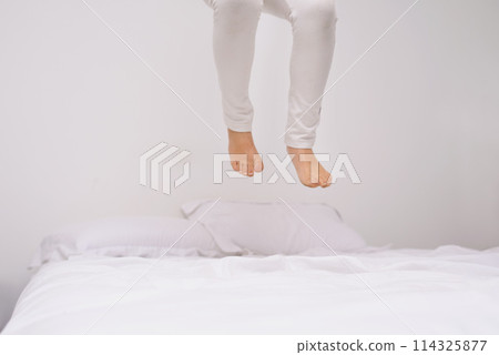 Jumping, bed and kid with fun, energy and morning in a bedroom with game and feet. Youth, hop and home with a excited child on a duvet in air with crazy play, leap and legs in house with white wall 114325877