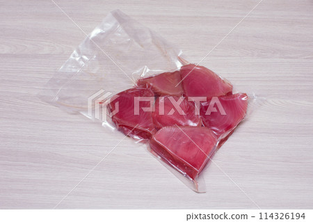 vacuum-packed tuna steaks on a light wooden surface 114326194
