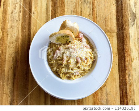 Pasta carbonara in a plate top view on a wooden background with slices of toasted bread Pasta carbonara in a plate top view on a wooden background with slices of toasted bread 114326195