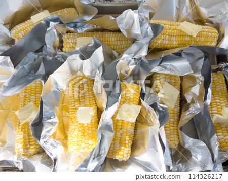 This image showcases fresh corn on the cob, neatly arranged in vacuum-sealed plastic packaging to preserve its freshness and flavor, ready for distribution or sale. This image showcases fresh corn on the cob, neatly arranged in vacuum-sealed plastic packaging to preserve its freshness and flavor, ready for distribution or sale. 114326217