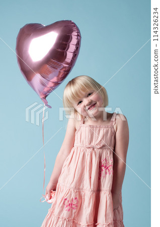 Heart balloon, happy and portrait of young girl on studio background for mockup, birthday and love. Female child, celebration and smile by blue backdrop for event, party and holiday or festival Heart balloon, happy and portrait of young girl on studio background for mockup, birthday and love. Female child, celebration and smile by blue backdrop for event, party and holiday or festival 114326234