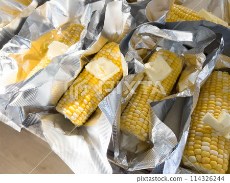 This image showcases fresh corn on the cob, neatly arranged in vacuum-sealed plastic packaging to preserve its freshness and flavor, ready for distribution or sale. 114326244