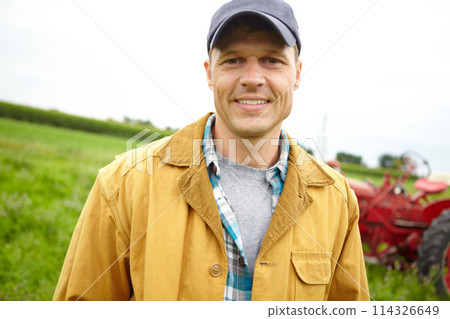 Working on the farm is my favourite thing to do. Portrait of a happy farmer in a field with a tractor parked behind him - Copyspace. Working on the farm is my favourite thing to do. Portrait of a happy farmer in a field with a tractor parked behind him - Copyspace. 114326649