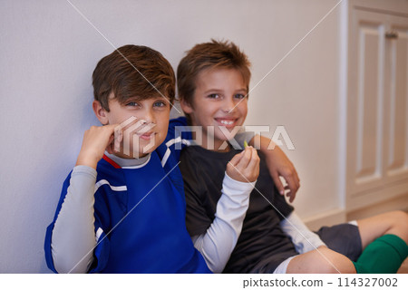 Children, portrait and friends with food in sports uniform for relax break in apartment or match, training or exercise. Male people, boys and face or eating snack in house or soccer, practice or meal 114327002