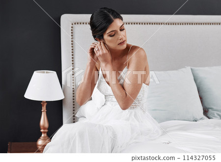 Luxury, jewellery and bride in bedroom at wedding, event or dressing in rich fashion for marriage. Bridal, style and girl in gown on bed with vintage, retro or diamond earrings in outfit at hotel Luxury, jewellery and bride in bedroom at wedding, event or dressing in rich fashion for marriage. Bridal, style and girl in gown on bed with vintage, retro or diamond earrings in outfit at hotel 114327055