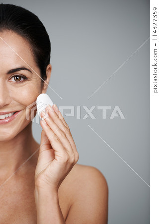 Mature woman, pad and portrait in studio, skin care and facial treatment on gray background. Female person, cotton and swab for grooming on half face, mockup space and dermatology to remove makeup 114327359