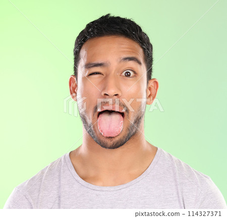 Man, portrait and silly in studio, tongue and goofy comic or funny face on green background. Male person, mockup space and wink for joke or comedy, student and humor for crazy character and emoji Man, portrait and silly in studio, tongue and goofy comic or funny face on green background. Male person, mockup space and wink for joke or comedy, student and humor for crazy character and emoji 114327371