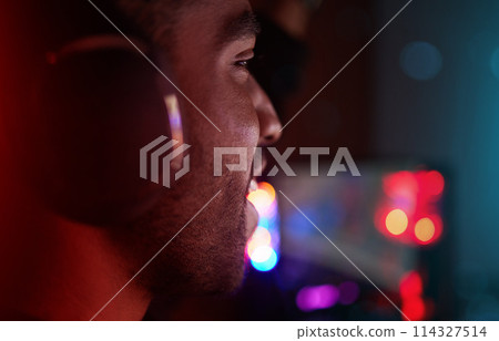 Gaming, headphones and man in esports at night in competition with online video games. Gamer, nerd and person in dark room with neon lights and live streaming cyber contest on computer in home 114327514