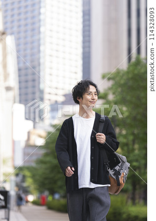 A man in his 30s walking down the street 114328093