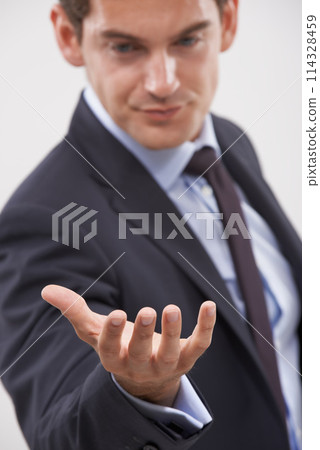 Businessman, palm and hand with interaction for hologram or virtual display on a gray studio background. Isolated young man, user or business employee showing gesture sign, symbol or 3D technology Businessman, palm and hand with interaction for hologram or virtual display on a gray studio background. Isolated young man, user or business employee showing gesture sign, symbol or 3D technology 114328459