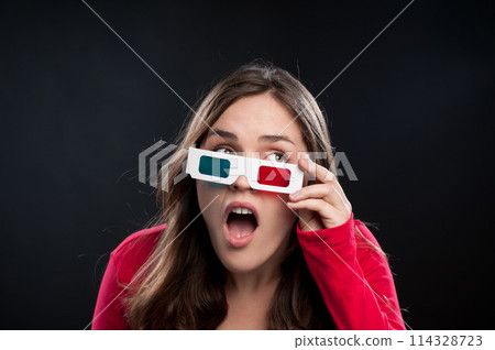 Woman, 3d glasses and surprise for watching movie, shocked or surreal in black studio background. Female person, wow and futuristic with color lens eyewear in cinema for mystery, film or mockup Woman, 3d glasses and surprise for watching movie, shocked or surreal in black studio background. Female person, wow and futuristic with color lens eyewear in cinema for mystery, film or mockup 114328723