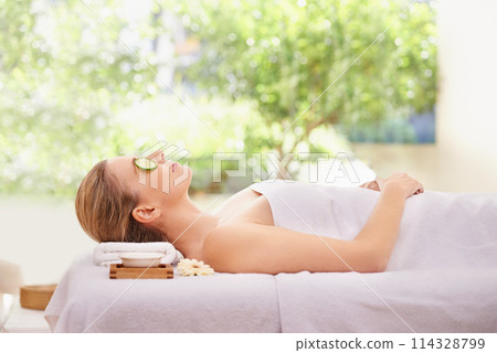 Woman, massage and spa with cucumber facial for skincare treatment or wellness, detox or stress relief. Female person, eyes closed and calm on table at zen resort for luxury, peace or comfortable Woman, massage and spa with cucumber facial for skincare treatment or wellness, detox or stress relief. Female person, eyes closed and calm on table at zen resort for luxury, peace or comfortable 114328799